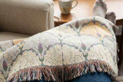 Plaid canapé douillet en laine aux tons neutres, posé sur un canapé beige dans un salon cosy